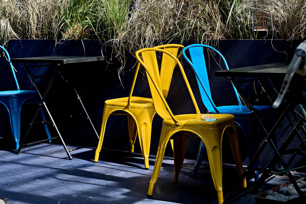 Vibrant metal chairs in an outdoor dining setting with plants in New York City.